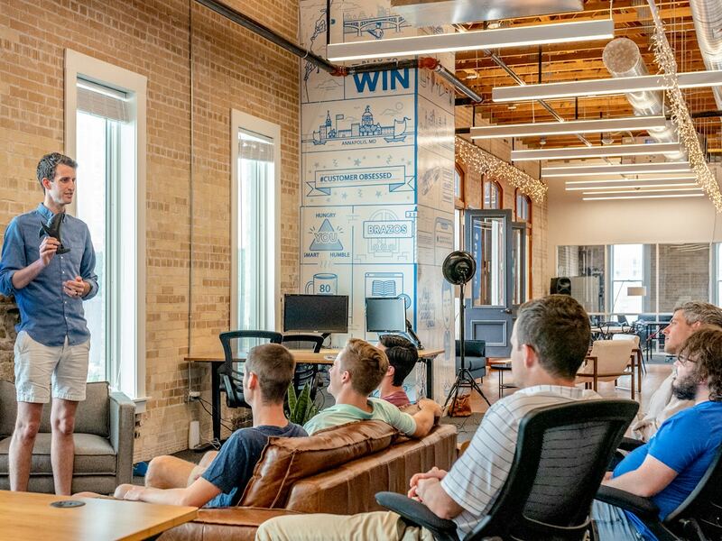 A team meeting in a bright, open office with a presenter at the front