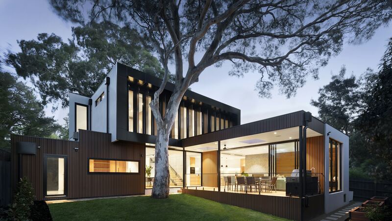 A modern home at dusk with warm light glowing from every window